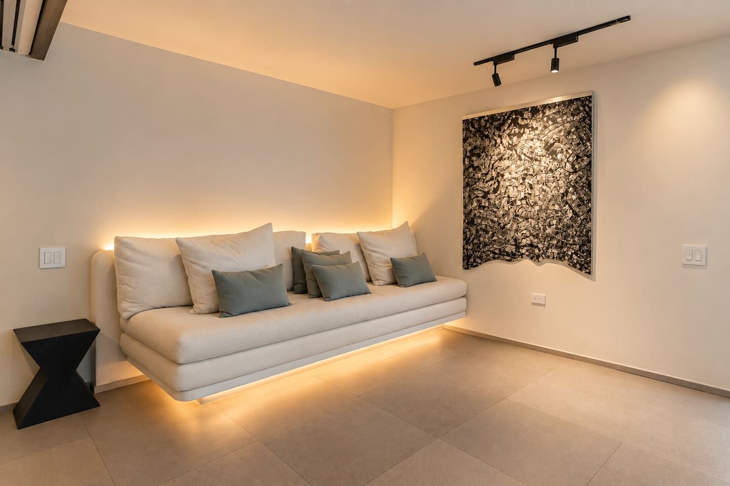 A modern living room with a sofa, a decorative wall piece, and a black side table.