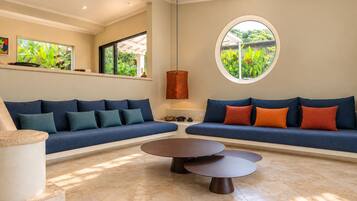 Una sala de estar moderna con dos sofás, una mesa de centro y un ventanal con vistas a zonas verdes.