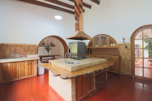A kitchen with a central island, wooden cabinets, a built-in oven, and a large window. - Cozy 12BR House with Pool in Pachacamac (Pachacámac)