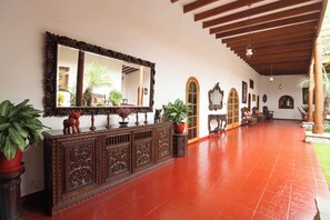 A spacious hallway with a large mirror, wooden furniture, and potted plants.