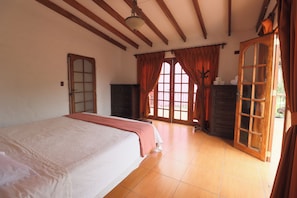 A bedroom with a large bed, wooden wardrobe, and a double door leading to an outdoor area. - Cozy 12BR House with Pool in Pachacamac (Pachacámac)