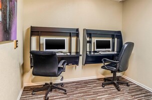 Una habitación de hotel con dos escritorios, cada uno con una computadora y teclado, y dos sillas de oficina negras.