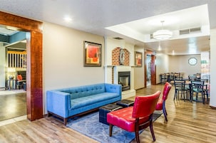 Una sala de estar moderna con un sofá azul, sillas rojas, una chimenea y un comedor con mesas y sillas.