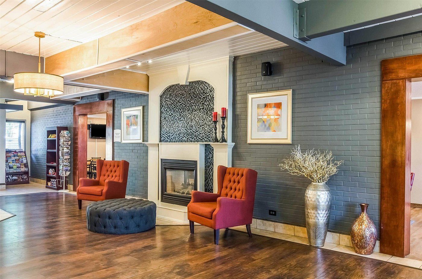 A spacious living area with a fireplace, two armchairs, a coffee table, and a bookshelf.