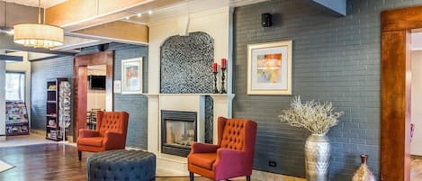 A spacious living area with a fireplace, two armchairs, a coffee table, and a bookshelf.