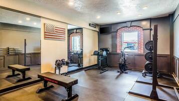 A gym with weightlifting equipment, a bench, and a mirror reflecting the American flag.
