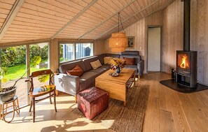 A modern living room with a wooden ceiling, a sofa, a coffee table, a fireplace, and a view of the outdoors. - Pet friendly home in Sydals with sauna (Sydals)