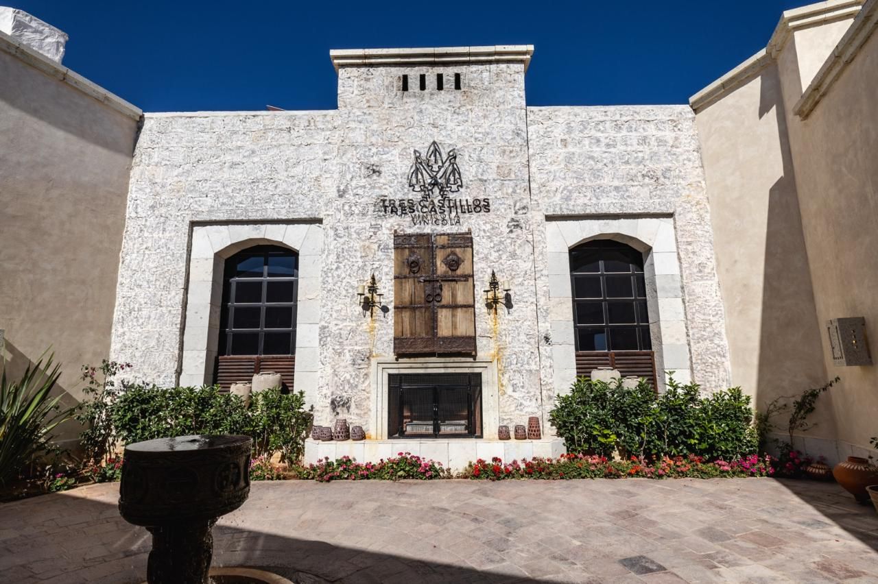 Un edificio con fachada de piedra, una entrada central con puerta de madera y dos ventanas de arco a cada lado.