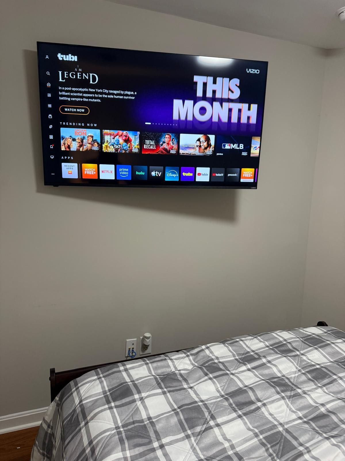 A flat-screen TV mounted on a wall displaying a streaming service interface with various content options.