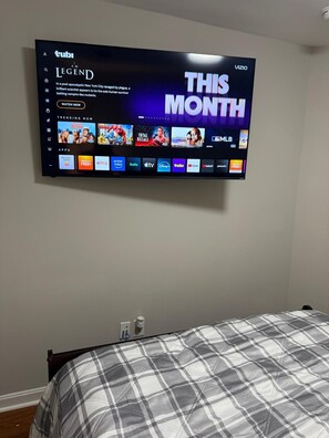 A flat-screen TV mounted on a wall displaying a streaming service interface with various content options.