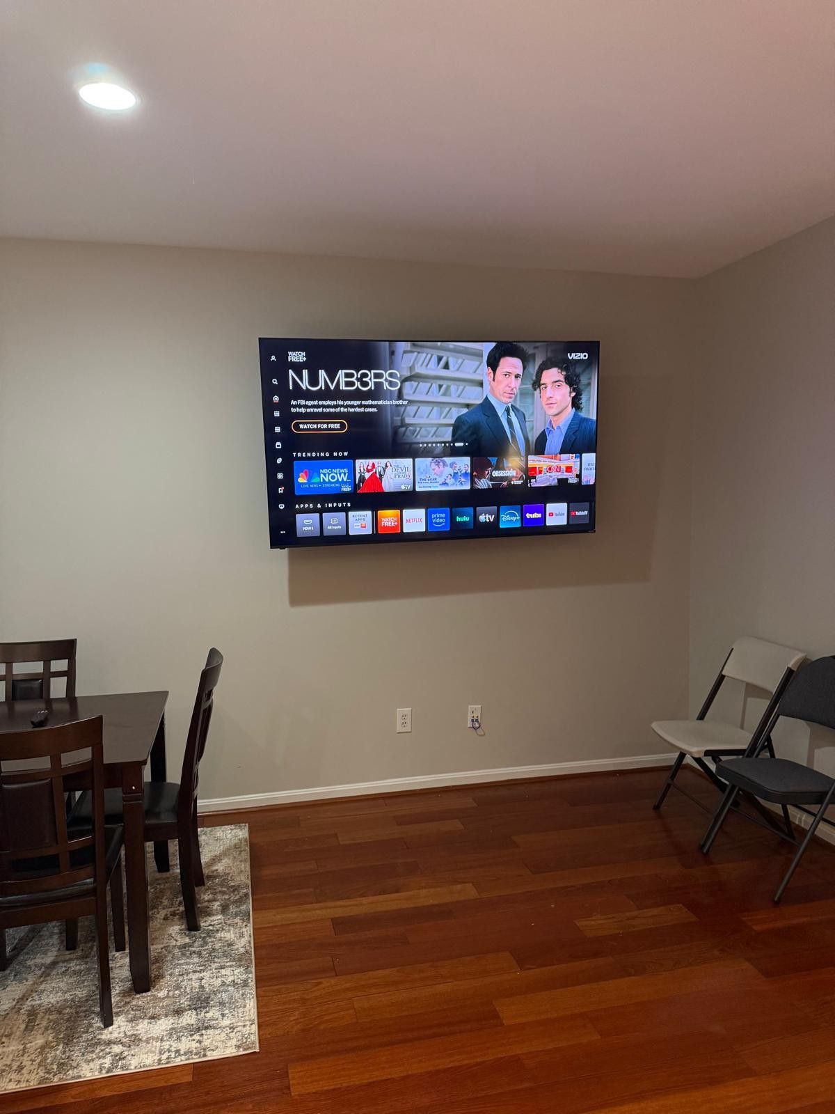 A flat-screen TV mounted on a wall displaying a show with two characters.