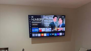 Een flatscreen-tv aan een muur, waarop een programma met twee personages te zien is.