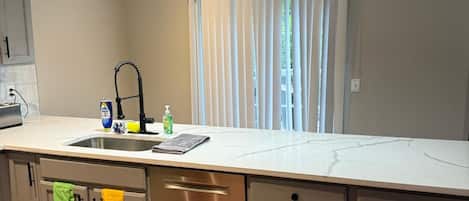 A modern kitchen with a central island, stainless steel appliances, and pendant lighting.