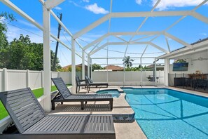 A covered outdoor swimming pool with lounge chairs and a patio area. - 4BR Heated Pool w BBQ in Central Area (Pinellas Park)