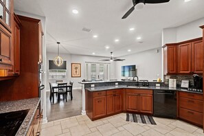 Une cuisine moderne avec des meubles en bois, une cuisinière noire et un coin repas comprenant des chaises et une table.
