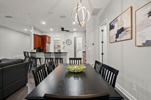 A modern dining area with a dark wooden table, black chairs, and a decorative bowl centerpiece. - 4BR Heated Pool w BBQ in Central Area (Pinellas Park)