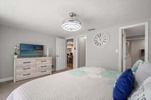 A bedroom with a bed, dresser, television, and a clock on the wall. - 3BR Screened Heated Saltwater Pool • BBQ (Port Richey)