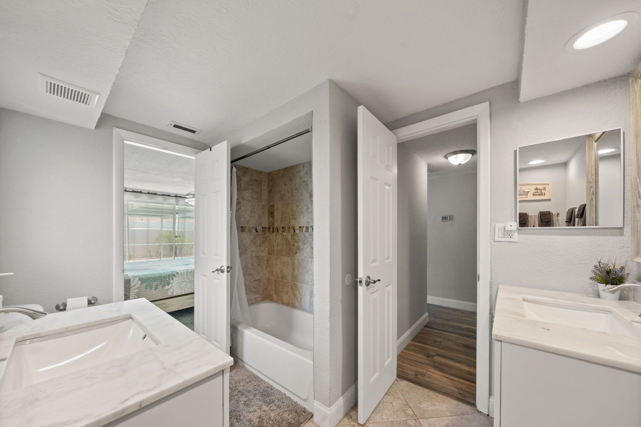 A modern bathroom with a walk-in shower, a bathtub, and two sinks.