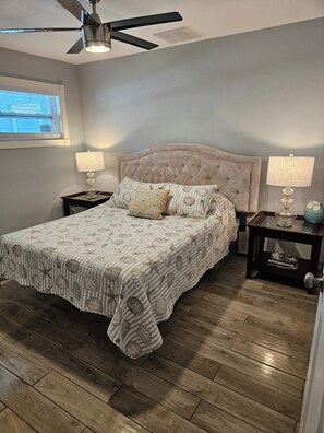 A bedroom with a bed, two nightstands, a ceiling fan, and a window. - 3BR Waterfront + Private Pool | Port Richey (Port Richey)