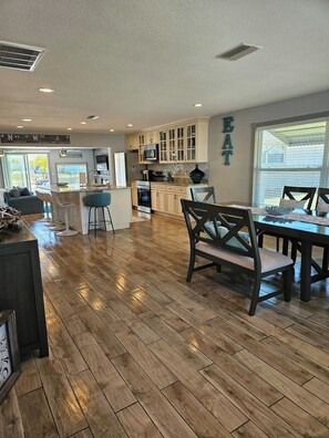 A spacious kitchen with wooden flooring, a dining area with a table and chairs, and a view of the outdoors. - 3BR Waterfront + Private Pool | Port Richey (Port Richey)