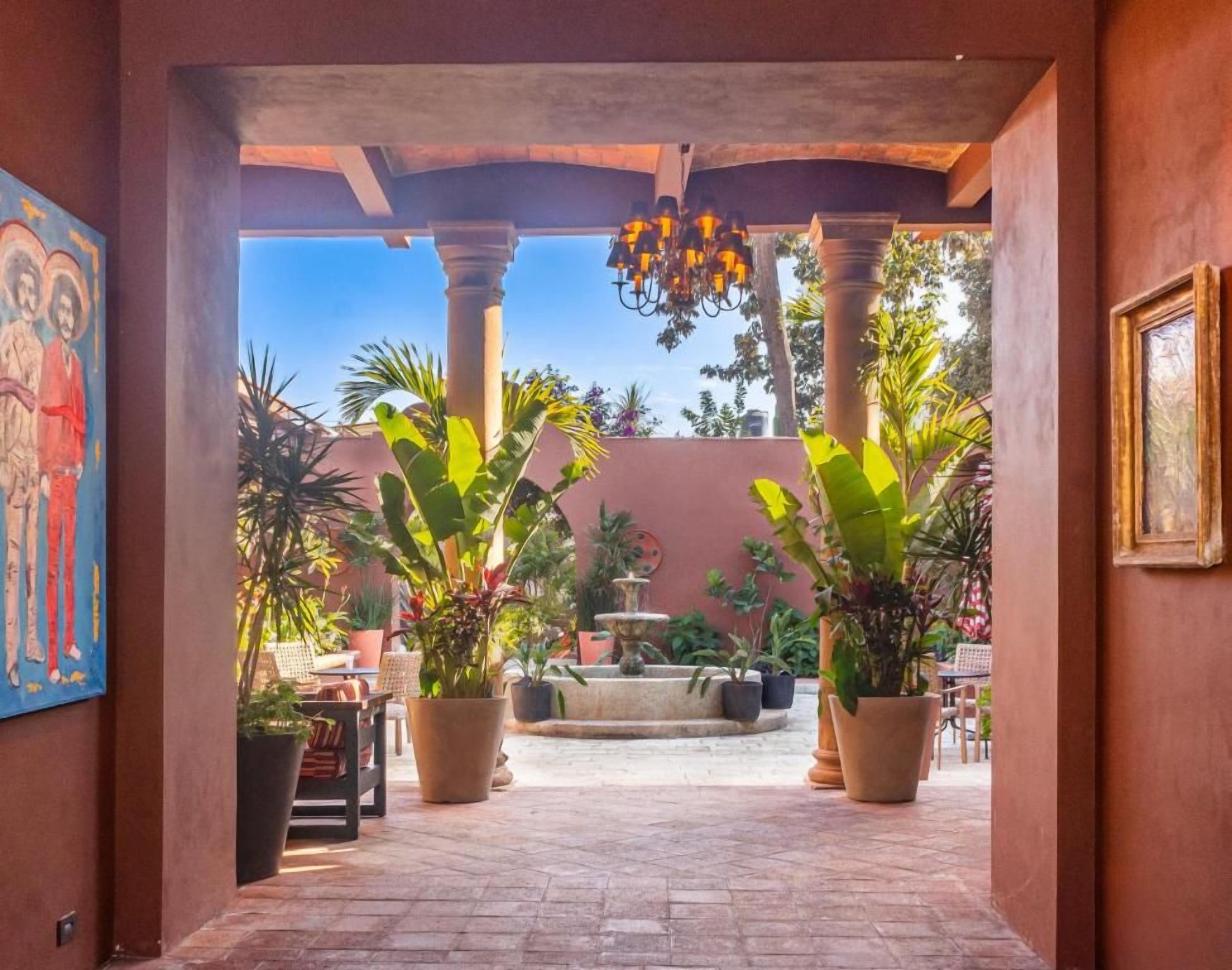 An outdoor courtyard with a fountain, potted plants, and a dining area.