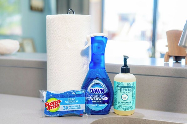A bathroom counter with a roll of toilet paper, a blue Dawn dish soap bottle, a Scotch-Brite Zero Scratch scrub, and a bottle of men's Dove hand soap. - BraveWave 1BR King Bed Bay Views Pool & Pier at Laguna Reef (Rockport)