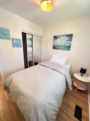 A bedroom with a bed, a bedside table, a lamp, and a painting on the wall.