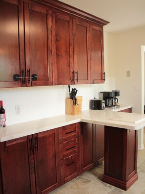 A kitchen with wooden cabinets, a countertop, and a coffee maker.