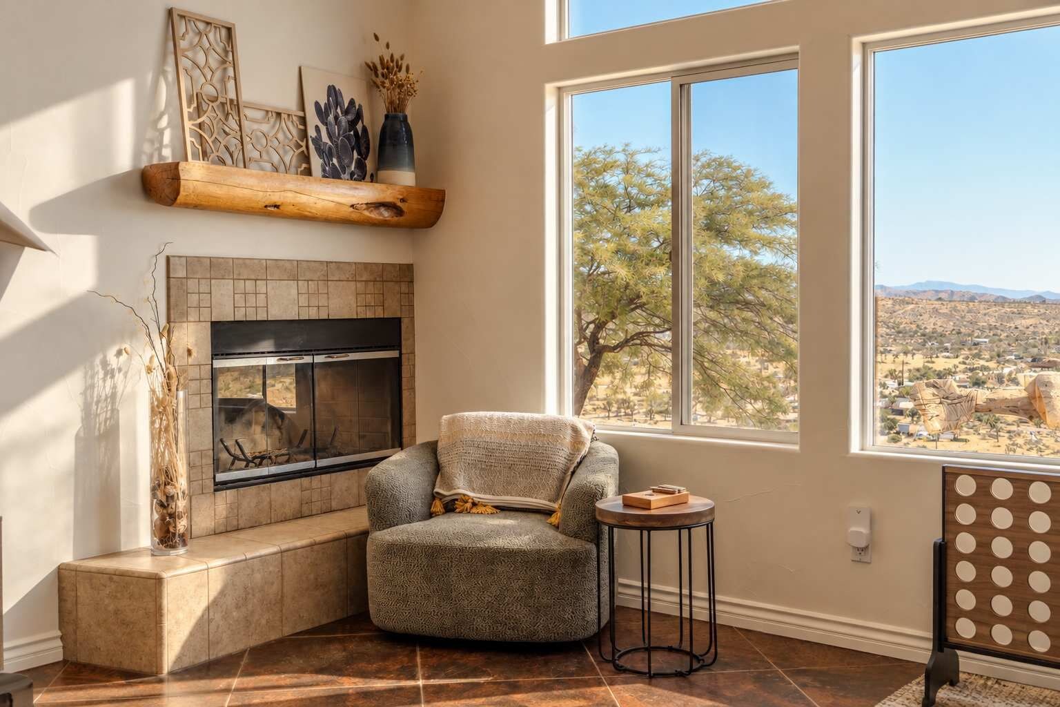 Uma sala de estar aconchegante com lareira, uma poltrona confortável e uma janela grande com vista para a paisagem do deserto.