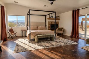Ein Schlafzimmer mit Himmelbett, Kamin, Blick ins Freie und einem großen Fenster.