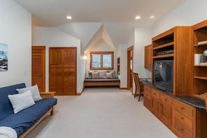 Ein Zimmer mit einer Couch, einem Holzschrank, einem Fernseher und einem Fenster.