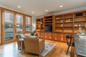 Ein geräumiges Wohnzimmer mit einer großen Holz-Unterhaltungsecke, einem Fernseher und einem Essbereich mit Tisch und Stühlen.