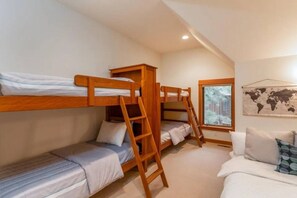 Ein Schlafsaalzimmer mit Etagenbetten, einer Leiter, einem Fenster mit Blick und einer Weltkarte an der Wand.