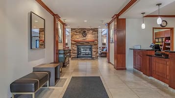 A hotel lobby with a fireplace, seating area, and a reception desk.