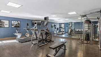 Un gimnasio con equipo de ejercicio, una banca y un espejo.