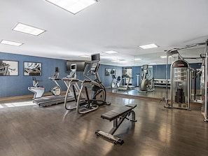 A gym with exercise equipment, a bench, and a mirror.