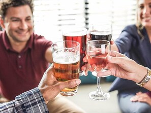 Un gruppo di persone brinda con bicchieri di birra e vino.