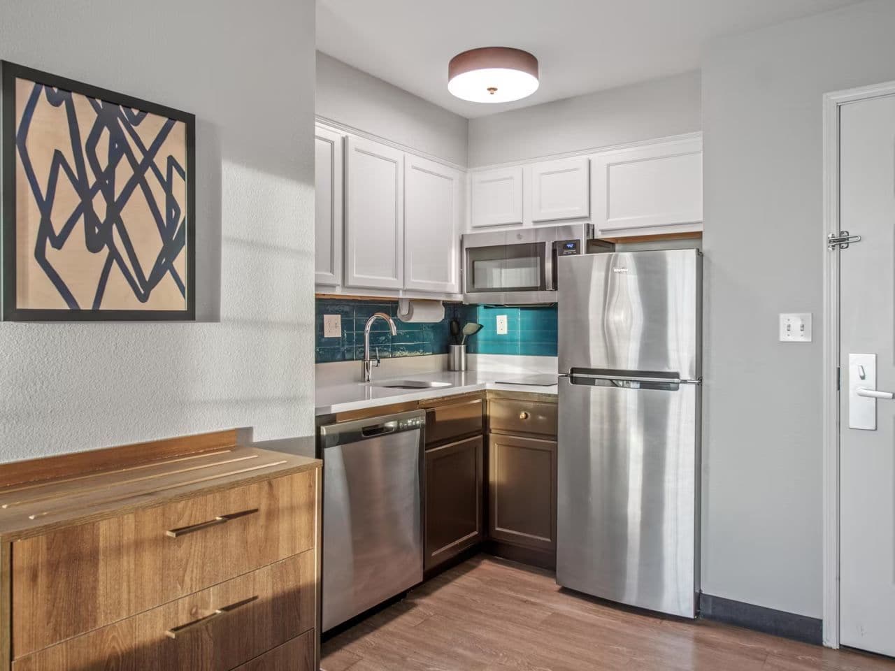 A compact kitchen with white cabinets, stainless steel appliances, and a wooden countertop.