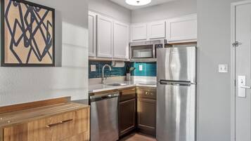 A compact kitchen with white cabinets, stainless steel appliances, and a wooden countertop.