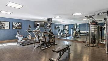 A gym with exercise equipment, a bench, and a mirror.