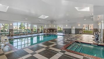 A large indoor swimming pool with checkered flooring, multiple windows, and a sunlit ceiling.