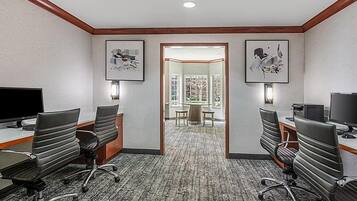 A conference room with two desks, chairs, and a carpeted floor.