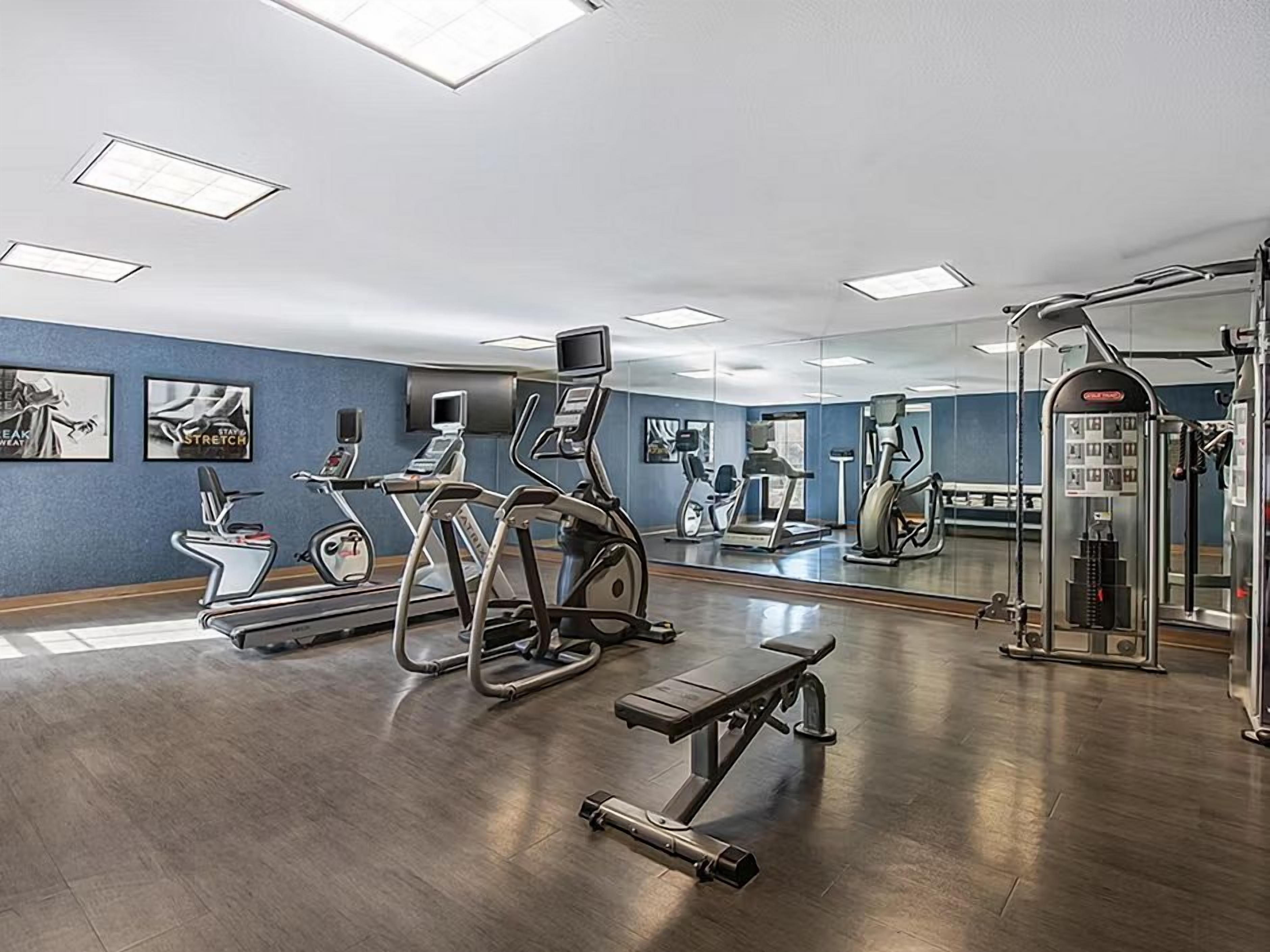 Un gimnasio con equipo de ejercicio, una banca y un espejo.