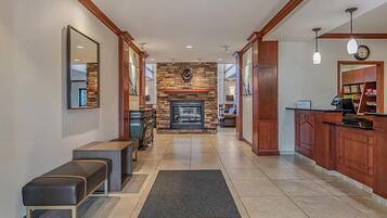 A hotel lobby with a fireplace, seating area, and a reception desk.
