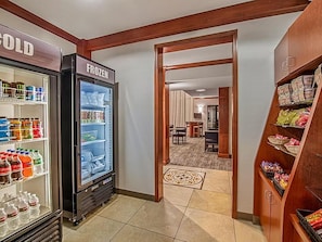 A hotel lobby with a refrigerated display case labeled 'COLD' and 'FROZEN,' a carpeted area leading to a dining room, and a snack shelf. - Accessible Suite w/ Kitchen, Pool & Free Breakfast (Rocklin)
