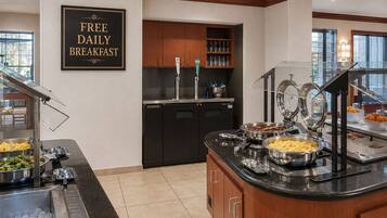 A breakfast buffet area with a sign stating 'FREE DAILY BREAKFAST.'