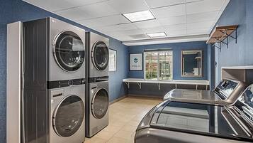 A laundry facility with stacked washers and dryers, a bench, and a window with a view.