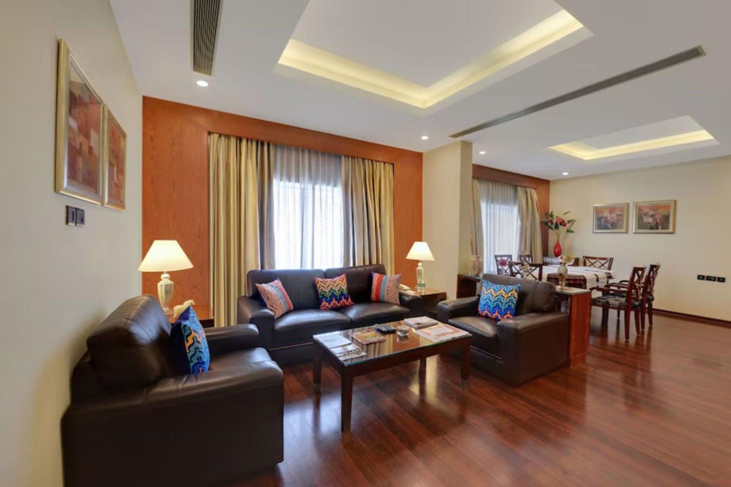 A modern living room with a sofa set, coffee table, and dining area with chairs.