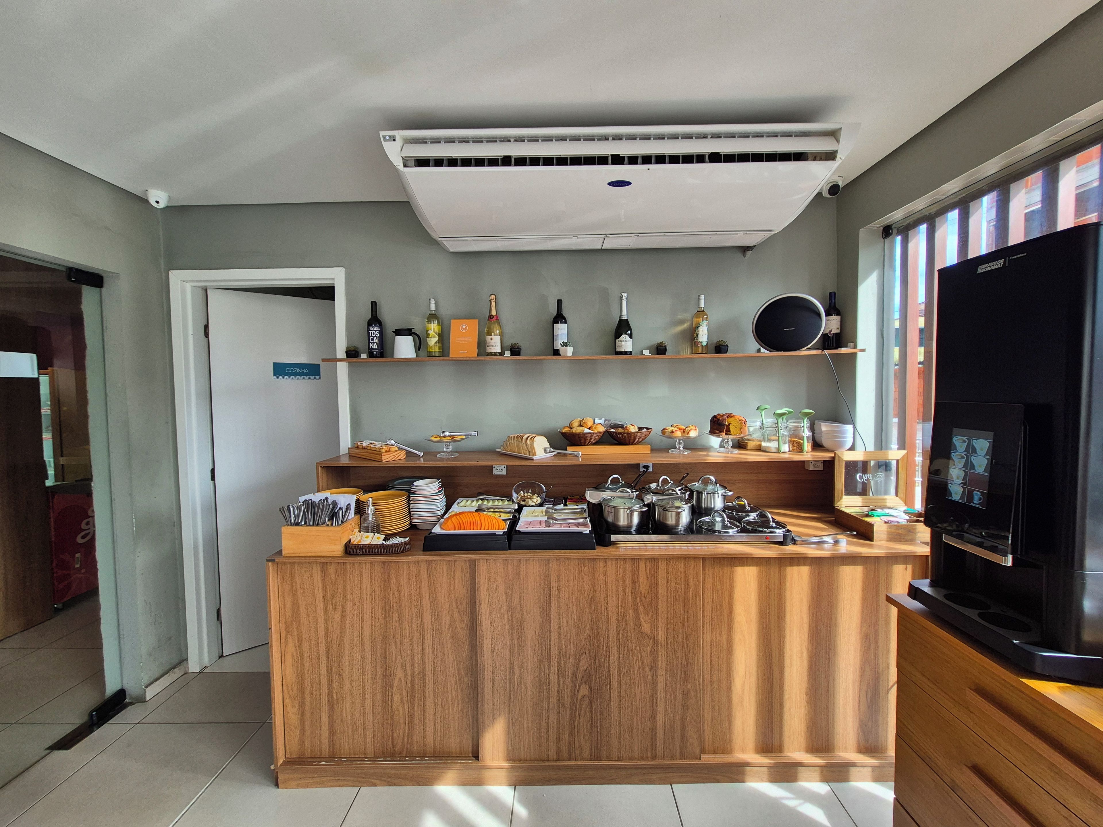 Quarto de hotel com cozinha compacta, espaço para café e vista para a cidade.