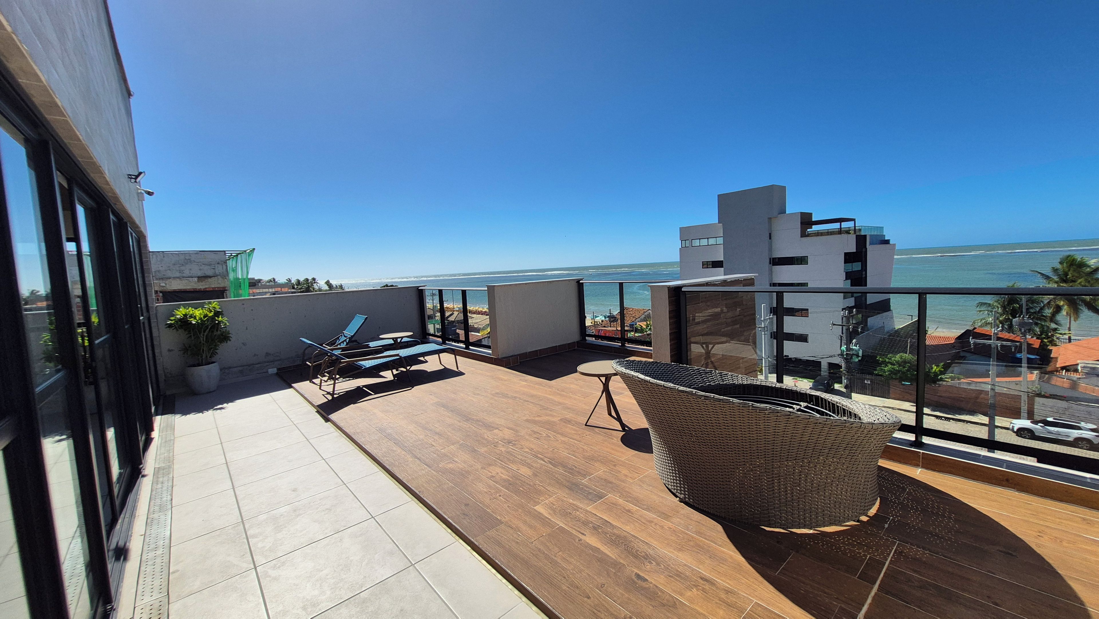 A balcony with a view of the ocean, furnished with chairs and a table.